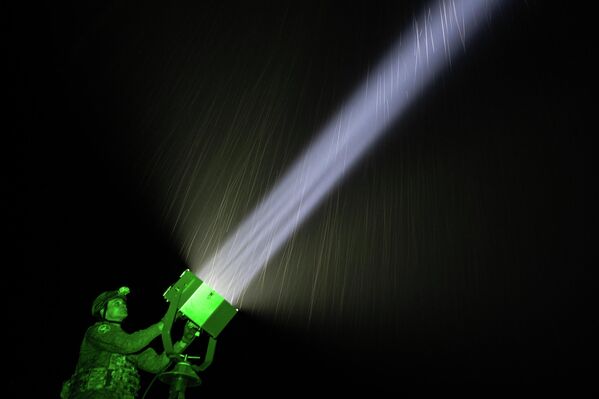 في الصورة يظهر جندي روسي وهو يقوم بتوجيه ضوء كبير باتجاه السماء - سبوتنيك عربي