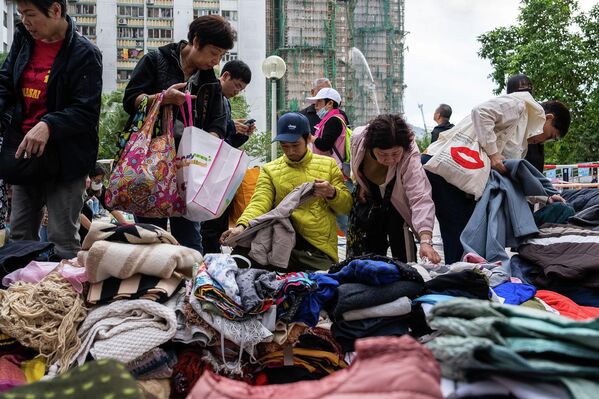 سكان يلتقطون الملابس المتبرع بها بالقرب من موقع الحريق في مجمع "وانغ فوك كورت " السكني الواقع في منطقة "تاي بو" في مقاطعة هونغ كونغ. - سبوتنيك عربي