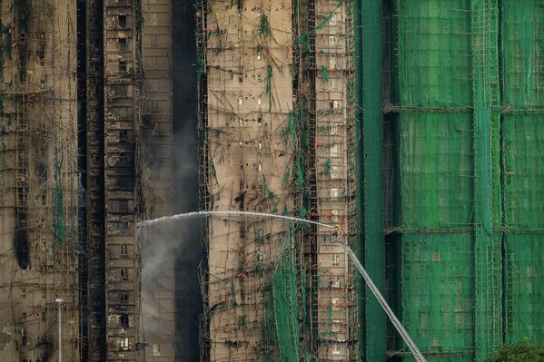 رجال الإطفاء يعملون على إخماد الحريق الذي اندلع أمس الأربعاء، في مجمع "وانغ فوك كورت " السكني الواقع في منطقة "تاي بو" في مقاطعة هونغ كونغ. - سبوتنيك عربي