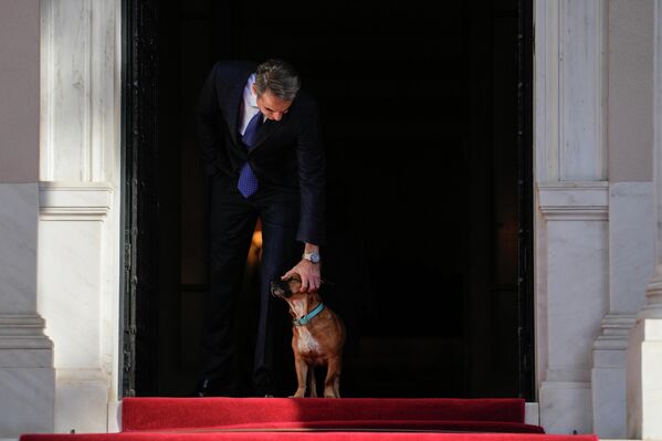 رئيس الوزراء اليوناني كيرياكوس ميتسوتاكيس يداعب كلبه بينات، قبل وصول الرئيس الروماني كلاوس يوهانيس، قبيل اجتماعهما في قصر ماكسيموس، في أثينا، يوم الجمعة 2 ديسمبر/كانون الأول 2022. - سبوتنيك عربي