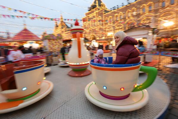 فتاة تقضي وقتًا ممتعًا في ساحة التزلج، وهي تجلس في أحد الألعاب المصصمة على شكل كوب شاي. - سبوتنيك عربي