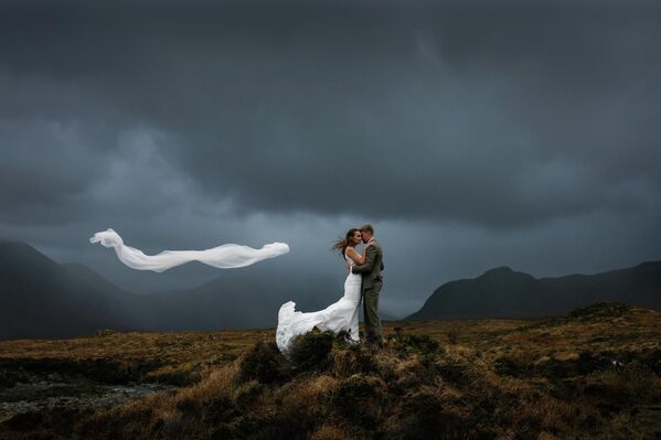 أولي برينس، الفائزة من المملكة المتحدة، عن صورة لزوجين يحتضنان بعضهما تحت سحب عاصفة داكنة في جبال كويلين في اسكتلندا. أولي برينس، الفائزة من المملكة المتحدة، عن صورة لزوجين يحتضنان بعضهما تحت سحب عاصفة داكنة في جبال كويلين في اسكتلندا. - سبوتنيك عربي