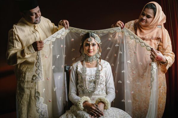 صورة لحظة، الفائزة بجائزة طاقم "أفعل" ماليزيا "حجاب البركات"، حيث يضع الوالدان الحجاب على رأس ابنتهما العروس قبل حفل الزفاف مباشرة. صورة لحظة، الفائزة بجائزة طاقم "أفعل" ماليزيا "حجاب البركات"، حيث يضع الوالدان الحجاب على رأس ابنتهما العروس قبل حفل الزفاف مباشرة. - سبوتنيك عربي