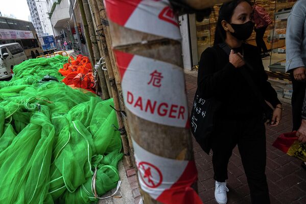 مشاة يمرون بجوار شبكات &quot;السقالات&quot; ومواد البناء التي تم إزالتها في منطقة خليج المحجر، ويظهر أيضا ملصق تم وضعه أثناء عمليات الترميم للتنبيه بوجود خطر لتوخي الحيطة والحذر. - سبوتنيك عربي