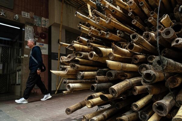أحد المشاة يمر بجانب الخيزران، الذي يقوم عمال البناء باستخدامه في عمليات الترميم. - سبوتنيك عربي
