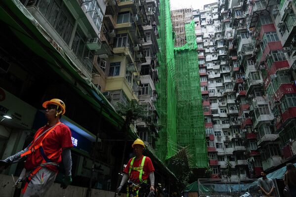 صورة تظهر عمال بناء أمام المباني التي يقومون بترميمها، ويظهر العمال في لباس العمل بالإضافه الى المعدات. - سبوتنيك عربي