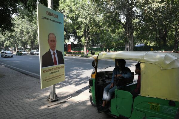 سكان محليون في أحد شوارع دلهي، حيث تظهر صورة ترحيب ببوتين على جانب الطريق. - سبوتنيك عربي