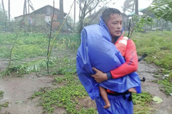 في هذه الصورة، يظهر رجل من فرق الإنقاذ التابعة لخفرالسواحل الفلبيني، وهو يحمل طفلًا صغيرًا، ليأخذه إلى مكان أكثر أمانا، وذلك بعد إعصار&quot;راجاسا&quot; في الفلبين. - سبوتنيك عربي