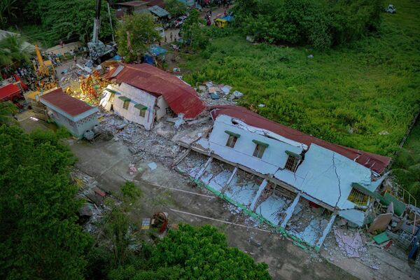 في هذه الصورة الجوية، يظهر عمال الإنقاذ وهم يبحثون عن ناجين من تحت أنقاض المبنى السكني الذي انهار في الفلبين جراء الزلزال الذي ضرب المنطقه بقوة 6.9. - سبوتنيك عربي