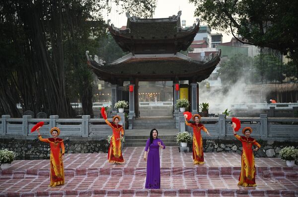 فتيات في ساحة "معبد الأدب" في هانوي، في فيتنام، ويظهر في الصورة، فتاة في لباس بنفسجي اللون، و4 فتيات في لباسٍ موحد اللون يحملن بأيديهن مراوح يدوية حمراء اللون. - سبوتنيك عربي