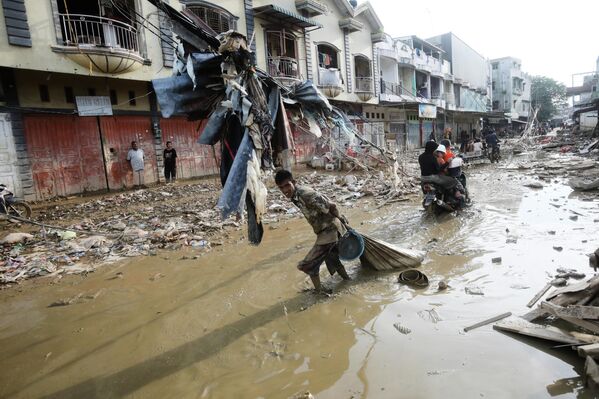 أحد الناجين يسحب كيساً من الأشياء التي تم إنقاذها عبر الوحل في منطقة تضررت من الفيضانات المفاجئة في آتشيه تاميانغ، في جزيرة سومطرة، إندونيسيا، الخميس 4 ديسمبر 2025. - سبوتنيك عربي