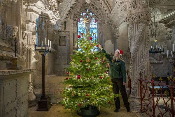 المرشدة السياحية ميغان كينغهورن تضع اللمسات الأخيرة على شجرة عيد الميلاد في مصلى السيدة العذراء بكنيسة روسلين في ميدلوثيان.تأسست الكنيسة عام 1446 وظهرت في فيلم شفرة دافنشي، وتستقبل الزوار طوال الأعياد وتستضيف شعائر وحفلات موسيقية خاصة بالمناسبة. - سبوتنيك عربي