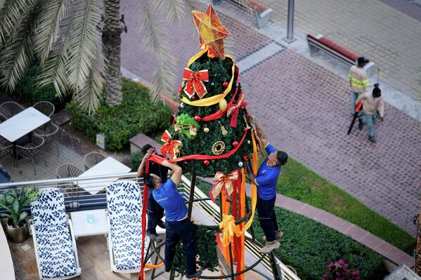 عمال يزينون شجرة عيد الميلاد في دبي، الإمارات العربية المتحدة. - سبوتنيك عربي