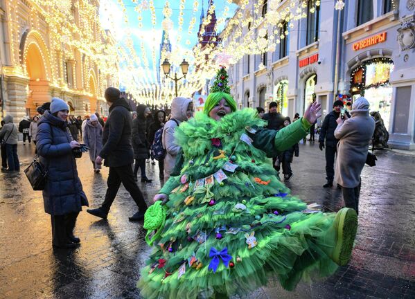 صورة تظهر المارة في شارع "نيكولسكايا" في موسكو، ويظهر في الصورة امرأة مرتدية فستانا على شكل شجرة عيد الميلاد. - سبوتنيك عربي