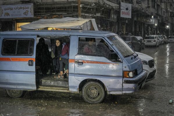 عائلة فلسطينية تختبئ داخل عربة بسبب تساقط المطر في مدينة غزة، فلسطين - سبوتنيك عربي