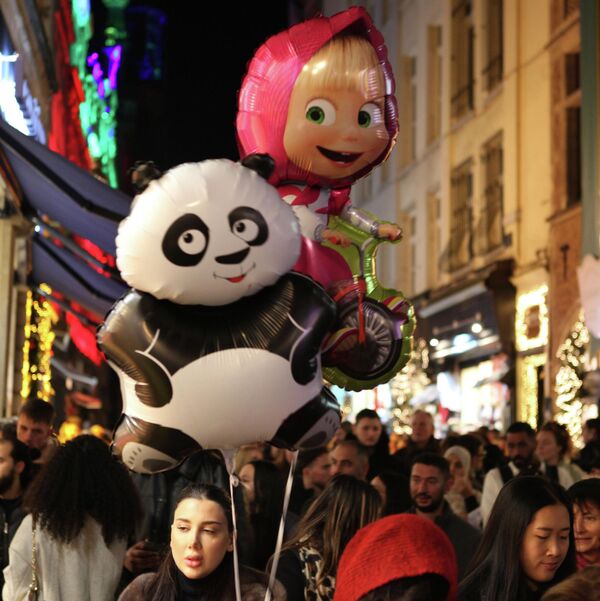 امرأة تحمل بالونا عملاقا على شكل باندا تسير في الشارع قبيل عيد الميلاد في بلجيكا - سبوتنيك عربي