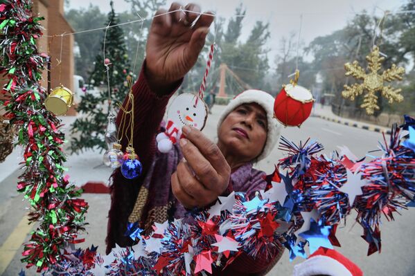 امرأة ترتب زينة احتفالات عيد الميلاد المقبلة في كاتدرائية القديس يوحنا في بيشاور في باكستان - سبوتنيك عربي