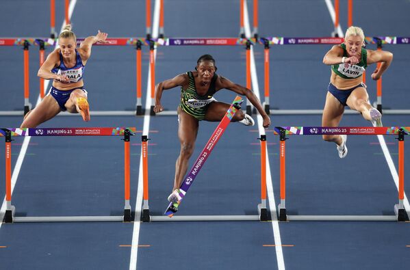 أكيرّا نوجنت، من فريق جامايكا (في الوسط) تتجاوز حاجزا خلال منافستها ضد لوتا هارالا من فريق فنلندا (على اليسار) وسارة لافين من فريق أيرلندا (على اليمين) في نصف نهائي سباق 60 مترا حواجز للسيدات، في نانجينغ في الصين - سبوتنيك عربي