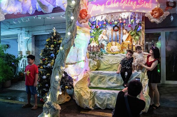 أناس يلتقطون صورا أمام منزل مزين بمشهدية الميلاد، عشية عيد الميلاد، في 24 ديسمبر/ كانون الأول 2025، في مدينة هوشي منه، فيتنام - سبوتنيك عربي