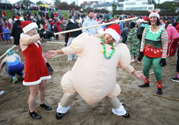 يستلقي الناس ويلعبون على الشاطئ ليلة عيد الميلاد في أيرلندا الشمالية  - سبوتنيك عربي