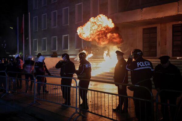 متظاهرون ألبانيون يلقون قنبلة حارقة خلف طوق أمني للشرطة، خلال اشتباكات في تظاهرة مناهضة للحكومة أمام مكتب رئيس الوزراء في العاصمة الألبانية تيرانا، يوم الاثنين 22 ديسمبر 2025، وسط احتجاجات على فضائح فساد وقضايا سياسية أوسع - سبوتنيك عربي