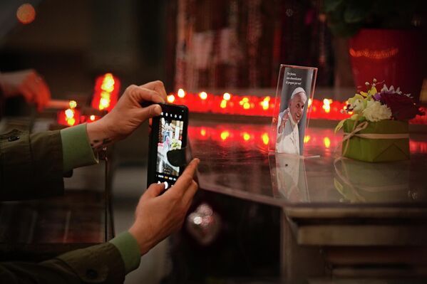 امرأة تلتقط صورة لصورة البابا الراحل فرنسيس الثاني، كُتب عليها "من فضلكم، لا تنسوا الصلاة من أجلي"، خلال قداس أُقيم على راحة نفسه في كنيسة "سانتو سبيريتو" في ساسيا خارج الفاتيكان - سبوتنيك عربي