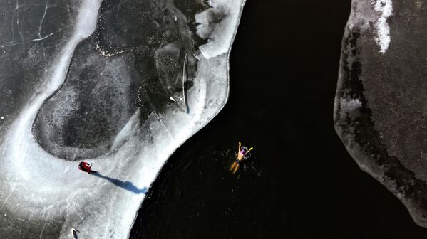 لقطة جوية، يظهر أحد هواة السباحة الشتوية وهو يسبح في مياه نهر متجمدة رغم البرد القارس في شنيانغ في مقاطعة لياونينغ الصينية - سبوتنيك عربي