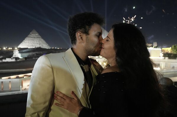 يتبادل السائحان الألمانيان جوشوا كورمان وزوجته دافينكا ميتودييفا قبلة، بينما تنطلق الألعاب النارية فوق موقع أهرامات "الجيزة" التاريخي، على مشارف القاهرة، مصر. - سبوتنيك عربي