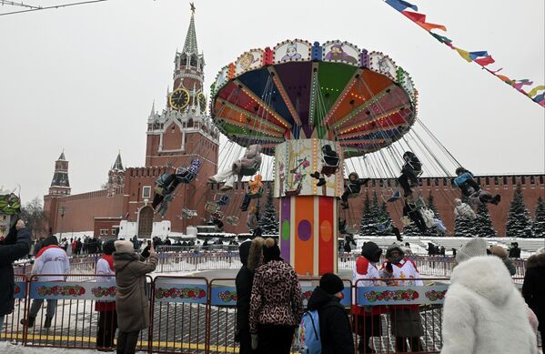 أشخاص يستمتعون بأوقاتهم على لعبة الدوامة في الساحة الحمراء بموسكو. - سبوتنيك عربي