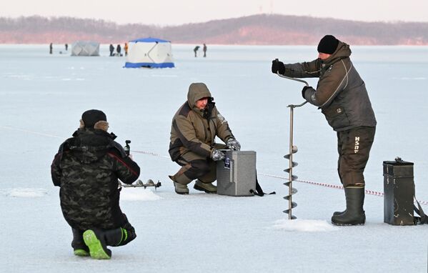 مشاركون في مهرجان صيد الأسماك الشتوي لكأس العمدة "كول سميلت" يصطادون السمك بملعقة الصيد الخاصة في خليج برازنيكوف في فلاديفوستوك. - سبوتنيك عربي