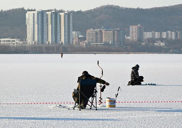 مشاركون في مهرجان صيد الأسماك الشتوي لكأس العمدة "كول سميلت" يصطادون السمك فوق الجليد في خليج برازنيكوف في فلاديفوستوك. - سبوتنيك عربي