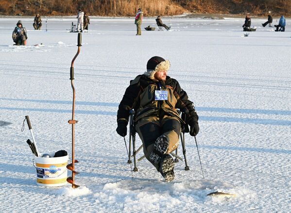 مشارك في مهرجان صيد الأسماك الشتوي لكأس العمدة "كول سميلت" في صيد الأسماك على الجليد باستخدام ملعقة الصيد الخاصة في خليج برازنيكوف في فلاديفوستوك. - سبوتنيك عربي