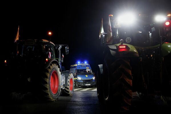تقف مركبة تابعة للدرك الوطني الفرنسي بينما تصطف الجرارات أمام الجمعية الوطنية، في احتجاجٍ من المزارعين الفرنسيين. - سبوتنيك عربي