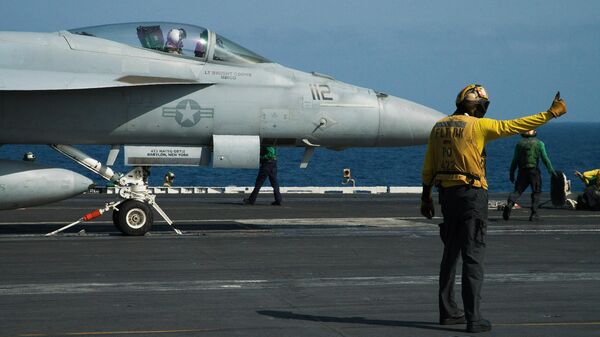 A crew member signals as a pilot prepares to launch an F/A-18 fighter jet on the deck of the USS Abraham Lincoln aircraft carrier in the Arabian Sea. File photo. - سبوتنيك عربي