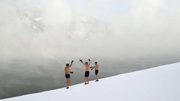 Члены клуба закаливания и зимнего плавания Дельфин разогреваются перед еженедельным заплывом в Енисее при температуре воздуха минус 33 градуса Цельсия в Дивногорске - سبوتنيك عربي