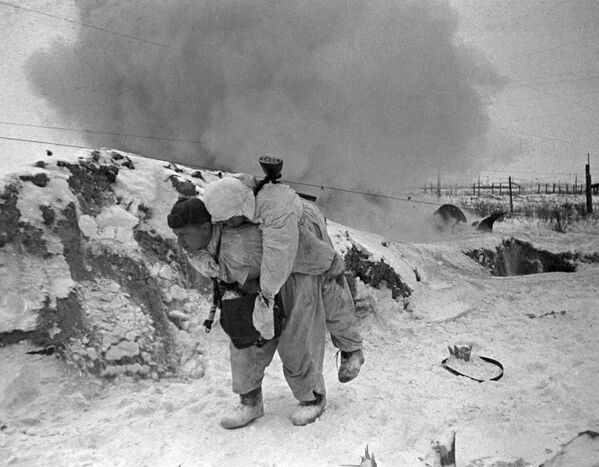 الحرب الوطنية العظمى، 1941-1945. معركة لينينغراد. مسعف سوفيتي يحمل جندياً جريحاً من ساحة المعركة خلال المعركة قرب لينينغراد. - سبوتنيك عربي
