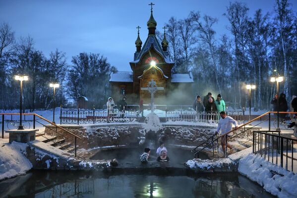الناس يقومون بالغطس خلال احتفال تقليدي بعيد الغطاس بالقرب من دير "أتشيرسكي" خارج مدينة أومسك السيبيرية في روسيا - سبوتنيك عربي