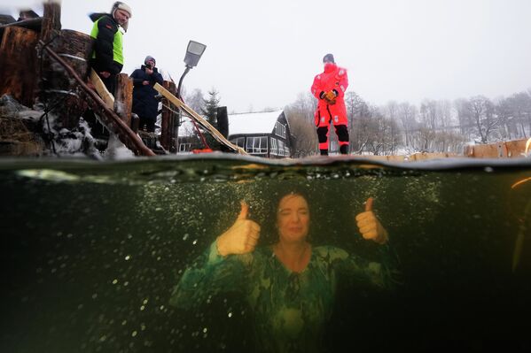 يغتسل أحد المؤمنين الأرثوذكس الروس في الماء المثلج احتفالاً بعيد الغطاس الأرثوذكسي عند فتحة جليدية في بركة بمدينة سانت بطرسبرغ، روسيا، يوم الاثنين 19 يناير 2026. - سبوتنيك عربي