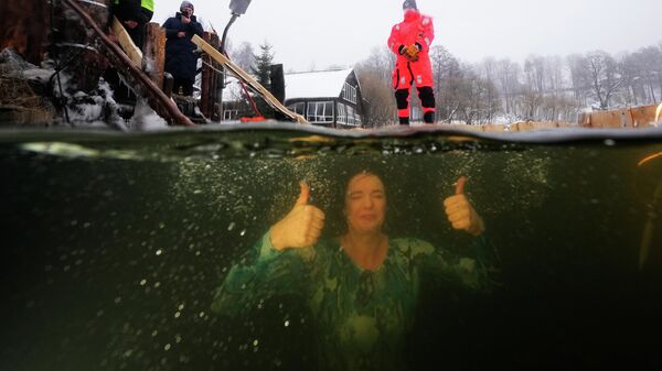 يغتسل أحد المؤمنين الأرثوذكس الروس في الماء المثلج احتفالاً بعيد الغطاس الأرثوذكسي عند فتحة جليدية في بركة بمدينة سانت بطرسبرغ، روسيا، يوم الاثنين 19 يناير 2026. - سبوتنيك عربي