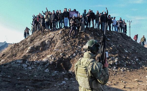 جندي تركي يحرس الحدود بينما يتجمع متظاهرون مؤيدون للأكراد على قمة تل في محاولة للوصول إلى المنطقة الحدودية خلال مظاهرة تضامنية مع الأكراد السوريين. - سبوتنيك عربي