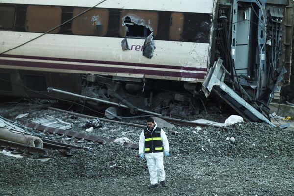 أحد أفراد الحرس المدني الإسباني يقف قرب حطام قطار في موقع حادث مميت شهد خروج قطارين عاليي السرعة عن السكة جنوبي إسبانيا، في يناير/كانون الثاني 2026، بحسب ما أظهرته صور من موقع الحادث. - سبوتنيك عربي