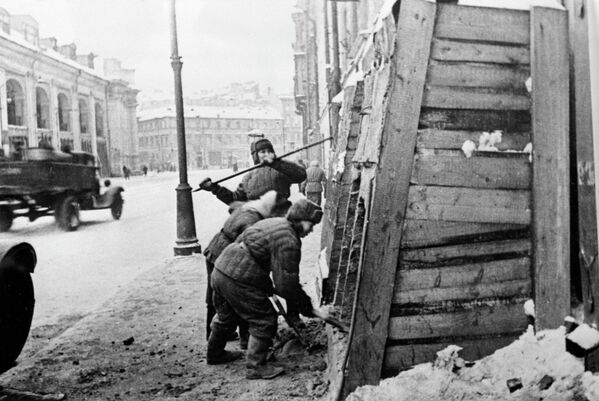 سكان لينيغراد يقومون بإزالة السواتر من أمام منازلهم في شارع "سادوفايا" بعد فك الحصار عن المدينة، حيث يظهر مبنى "غوستيني دفور" على يسار الصورة - سبوتنيك عربي