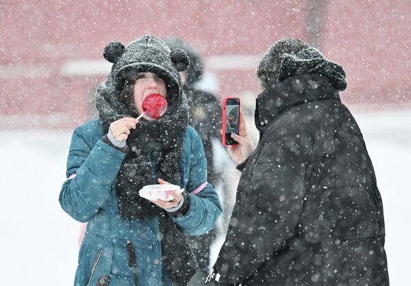 تساقط الثلوج في الساحة الحمراء وتظهر في الصورة فتاة تقوم بالتقاط صورة لزميلتها وهي تأكل الحلوى. تساقط الثلوج في الساحة الحمراء وتظهر في الصورة فتاة تقوم بالتقاط صورة لزميلتها وهي تأكل الحلوى. - سبوتنيك عربي