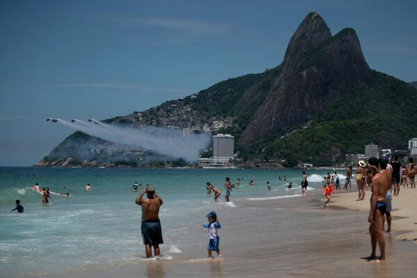 يشاهد الناس طائرات الهليكوبتر التابعة لسلاح الجو الإسباني "باترولا أسبا" وهي تؤدي عروضها فوق شاطئ إيبانيما في ريو دي جانيرو، الأربعاء، 28 يناير/كانون الثاني 2026. - سبوتنيك عربي