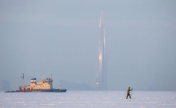 أحد سكان المدينة على خليج فنلندا المتجمد في سانت بطرسبورغ. في الخلفية: برج مجمع "لاختا سنتر" متعدد الوظائف للأعمال وكاسحة الجليد "كابتن كوسولابوف". - سبوتنيك عربي