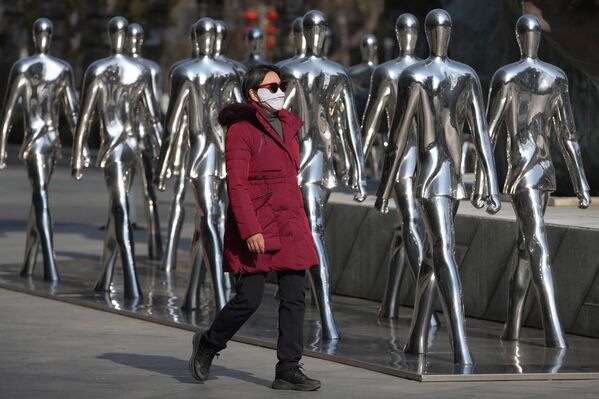 امرأة تمر أمام أعمال فنية على شكل إنسان معروضة خارج مركز تجاري في بكين، الصين، الثلاثاء، 27 يناير/كانون الثاني 2026. - سبوتنيك عربي