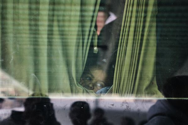 طفل فلسطيني ينظر من نافذة الحافلة التي تقله مع مرضى آخرين من خان يونس إلى معبر رفح، لتلقي العلاج في الخارج. - سبوتنيك عربي