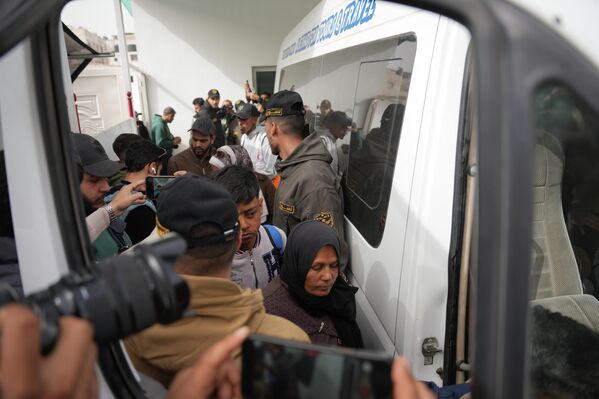شاب فلسطيني ووالدته يستقلان الحافلة في خان يونس للتوجه إلى معبر رفح، وسط جموع من المواطنين والصحفيين.  - سبوتنيك عربي
