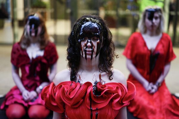 ناشطون يرتدون فساتين حمراء مزينة بالورود، ووجوههم مغطاة بدبس السكر، أمام مكاتب شركة "إكوينور" في لندن، بريطانيا، في احتجاجٍ على "التسرب النفطي"، وذلك مع اقتراب موعد حسم قرار الحكومة البريطانية بشأن الموافقة على حقل روزبانك النفطي أو رفضه. - سبوتنيك عربي