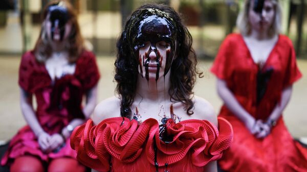 Активистки в платьях с красными розами и лицами, покрытыми патокой, сидят перед офисами компании Equinor, Великобритания - سبوتنيك عربي